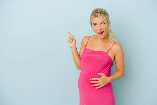 Młoda Rosjanka w ciąży odizolowana na niebieskim tle wskazując na bok - Zdjęcie, obraz