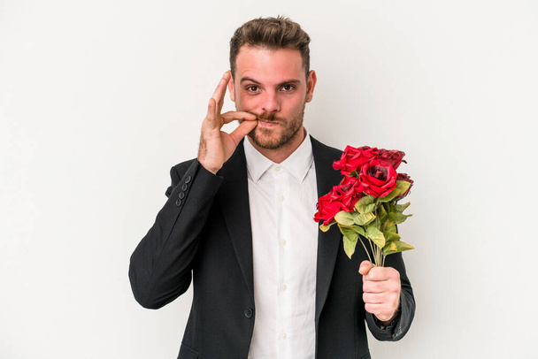 Fiatal kaukázusi férfi kezében csokor virág elszigetelt fehér háttér ujjak az ajkakon tartja a titkot. - Fotó, kép