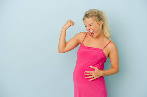 Young Russian woman pregnant isolated on blue background raising fist after a victory, winner concept. - Photo, Image