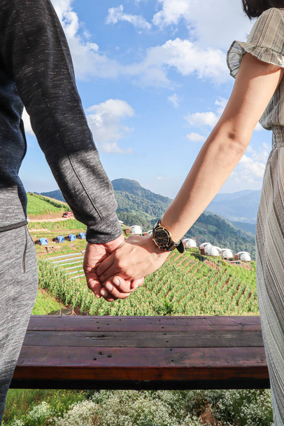 love couple standing lovingly holding hands and admiring beautiful scenery on balcony of their vacation home after happy vacation. concept love couple holding hands means love and care. - Photo, Image
