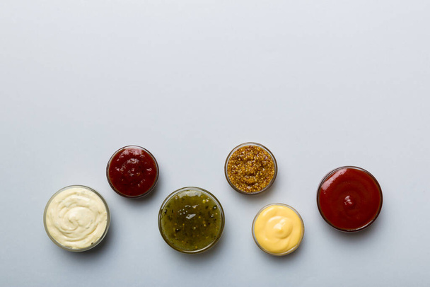 Diferentes tipos de salsas en cuencos en un tablero de color. Vista superior. varias salsas espacio de copia. - Foto, imagen