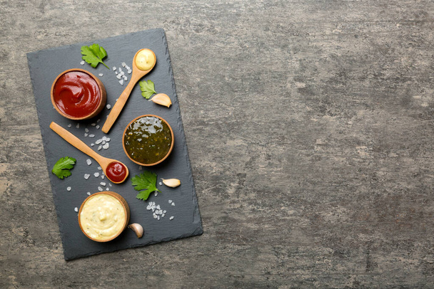 Veel verschillende sauzen en kruiden op tafel, plat uitzicht op het blad. sauzen op schaal, gezond concept. - Foto, afbeelding