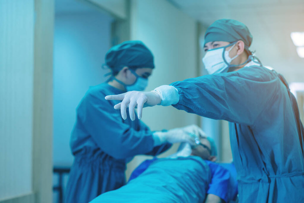 Врач, готовящий пациента к следующей процедуре в коридоре, бригада медиков толкает койку для носилок.. - Фото, изображение