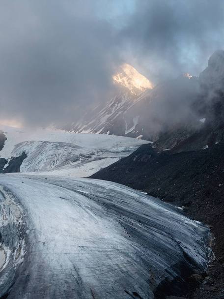 Soft focus. Twilight Mountains. Light on the glacier. Majestic glacier is illuminated by the bright golden evening sun. Vertical view. Big Aktru Glacier, Altai Mountains. - Zdjęcie, obraz