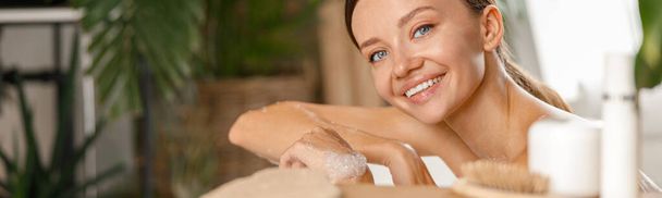 Egy csinos fiatal nő portréja, aki a kamerába mosolyog, miközben a trópusi gyógyfürdőben vigyáz a testére. - Fotó, kép