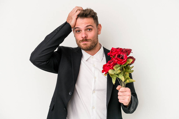 Young caucasian man holding bouquet of flowers isolated on white background being shocked, she has remembered important meeting. - Foto, Imagem