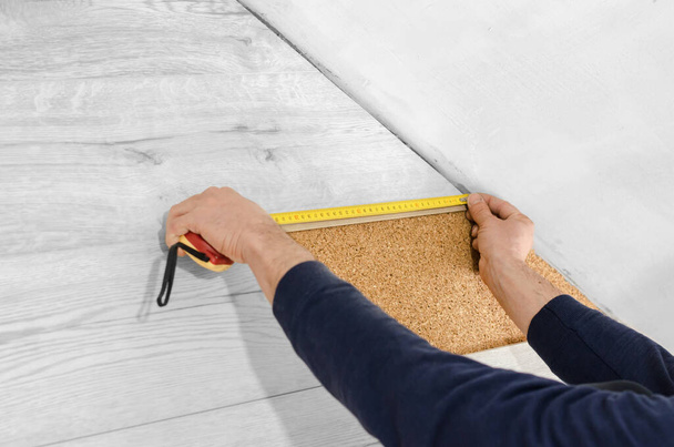 Unrecognizable man laying laminate flooring. Professional laying of flooring - laminate. Measuring tape on laminate floor plank - Φωτογραφία, εικόνα