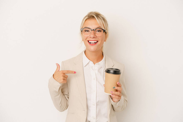 Joven mujer rusa de negocios sosteniendo tomar café aislado en el fondo blanco persona señalando a mano a un espacio de copia de la camisa, orgulloso y seguro - Foto, imagen