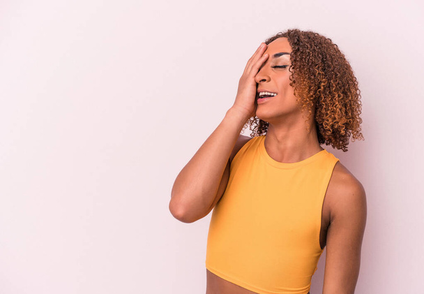 Young latin transsexual woman isolated on pink background laughing happy, carefree, natural emotion. - Φωτογραφία, εικόνα
