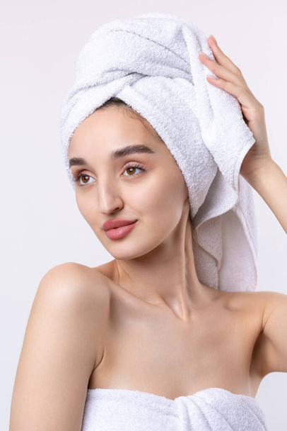 Beautiful girl with thick eyebrows and perfect skin at white background, towel on head, beauty photo. - Photo, image