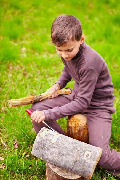 Boy sculpting in a log with a chisel - 写真・画像
