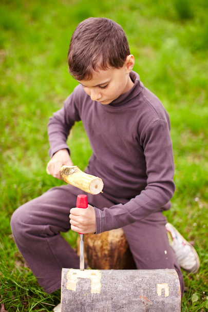 Boy sculpting in a log with a chisel - Fotó, kép