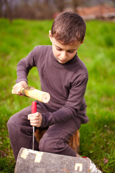 Boy sculpting in a log with a chisel - Fotó, kép