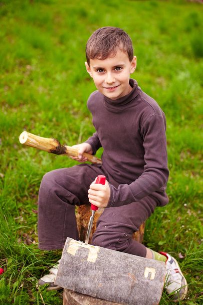 Boy sculpting in a log with a chisel - Foto, imagen