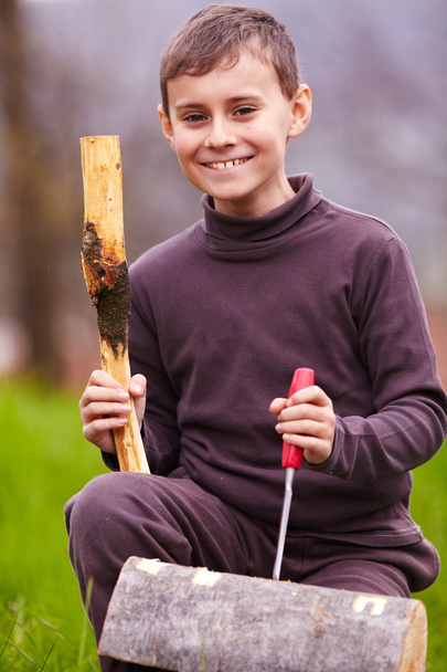 Boy sculpting in a log with a chisel - Foto, afbeelding