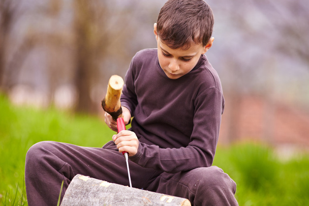 Boy sculpting in a log with a chisel - Фото, изображение