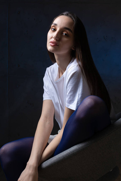 Ritratto di una giovane bruna con i capelli lunghi in studio. Foto drammatica in colori scuri. - Foto, immagini