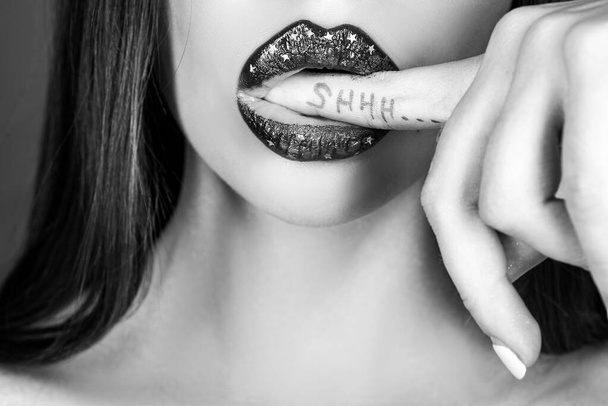 Shhh woman. Shh, Womens secrets. Female with finger in mouth. Closeup of young woman is showing a sign of silence with shhh written on the finger. - Φωτογραφία, εικόνα