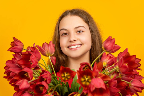 cheerful child hold spring tulip flowers on yellow background - Foto, afbeelding