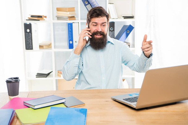 Happy guy talking on mobile phone working on laptop in office, business call - Photo, Image
