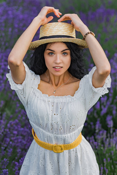 Lavender field. A girl with a basket and a straw hat picks flowers. - Foto, immagini