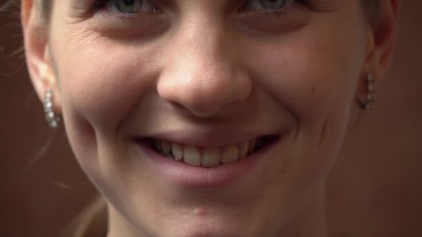 Twarz pięknej młodej kobiety patrzącej i uśmiechniętej do kamery - Materiał filmowy, wideo