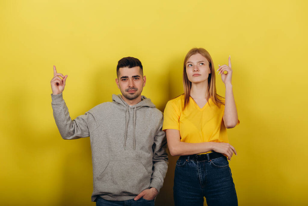 Two young beautiful people girl and guy standing on a yellow background. - Foto, immagini