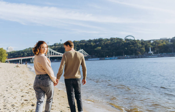 Feliz pareja romántica joven disfrutando de un hermoso paseo al atardecer en la playa. Concepto de estilo de vida vacacional - Foto, imagen