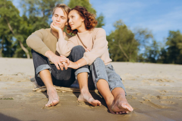 Male and female legs on the beach. Focus on the legs. People are out of focus. - Photo, Image