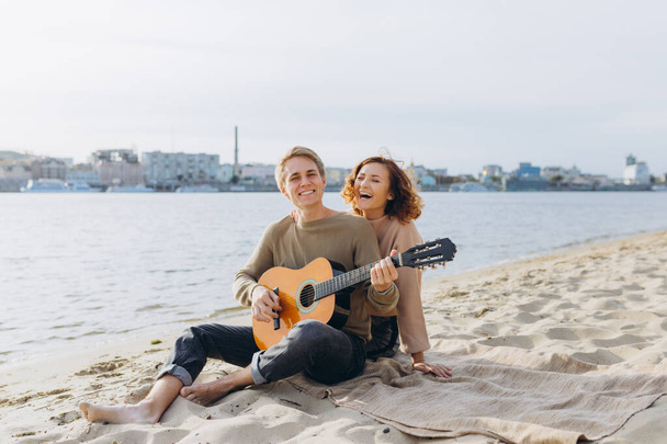 Um casal feliz apaixonado. Impressionante retrato sensual de um jovem casal. Jovem tocando guitarra para sua amada garota. - Foto, Imagem