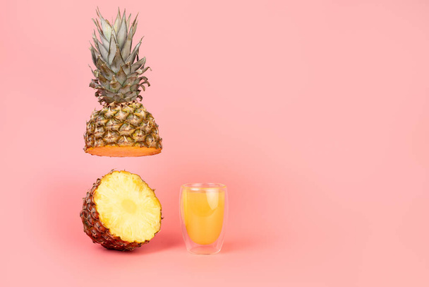 ananas ja lasillinen ananasmehua eristetyllä pastellin pinkillä taustalla kopiointitilalla. Minimaalinen hedelmä käsite. Ravitsemuksen käsite - Valokuva, kuva