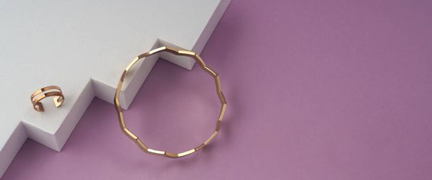 Panorama of Zig zag shape bracelet and golden ring on white geometric podium on pink background with copy space - Φωτογραφία, εικόνα