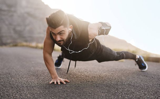 Endure every challenge and it will change you. Shot of a sporty young man doing pushups while exercising outdoors. - Photo, Image