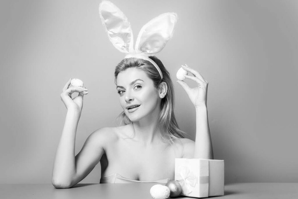 Woman with rabbit ears hold easter egg over pink background. - 写真・画像