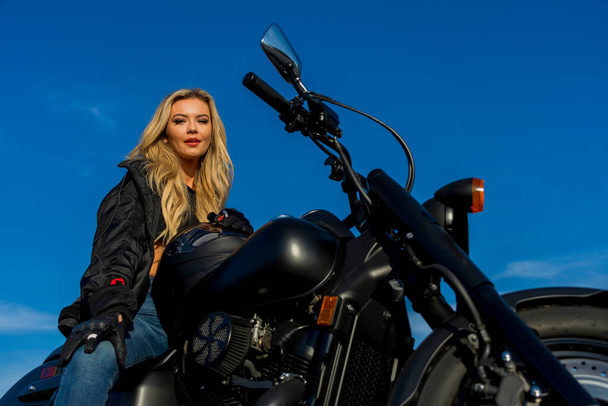 Une superbe mannequin blonde profite du plein air tout en conduisant sa moto.  - Photo, image