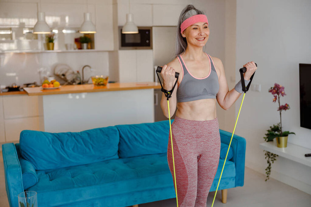 Radostná žena dělá cvičení s fitness lanem doma - Fotografie, Obrázek