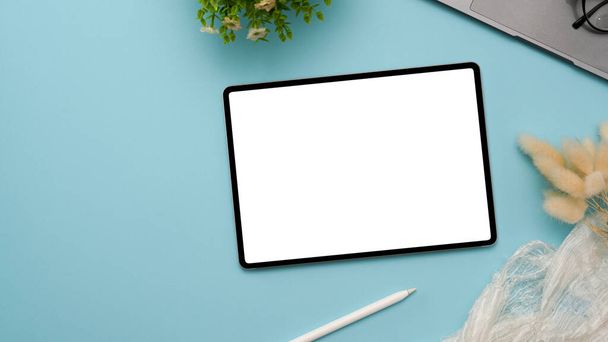 Nad hlavou záběr grafického tabletu touchpad bílá obrazovka mockup, pero stylus, notebook a dekor rostlina na pastelově modrém pozadí. - Fotografie, Obrázek