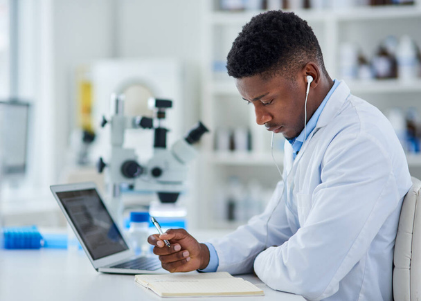 Forschung ist nicht zu ersetzen. Schnappschuss eines fokussierten jungen Wissenschaftlers, der an seinem Laptop arbeitet, während er in einem Labor sitzt. - Foto, Bild