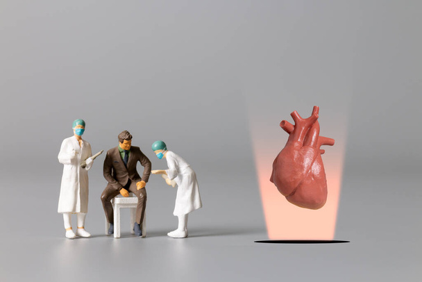 Miniaturmenschen, Doktor, der das menschliche Herz untersucht und behandelt, Konzept zum Weltgesundheitstag - Foto, Bild