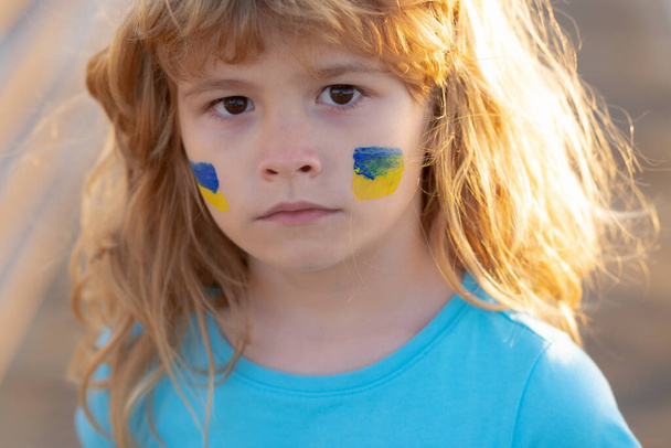 Ukraine flag on kids cheek. No war, stop war, russian aggression. Little ukrainian patriot. - Foto, Bild