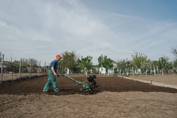 Man plowing the land in the garden on sky background - Photo, Image