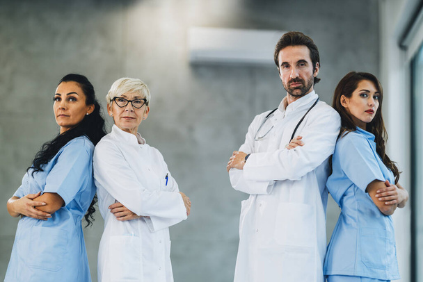 Portrait of a confident medical team of doctors and nurses standing with arms crossed in a hospital hallway and looks at camera. - Photo, Image