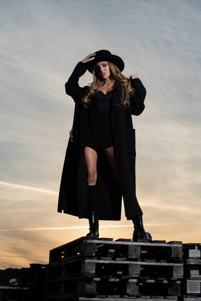 Sexy woman in black fashion coat, hat and black shoes boots. Beautiful young woman wearing fashionable spring clothes. Portrait of the fashion model in trendy dress. - Φωτογραφία, εικόνα