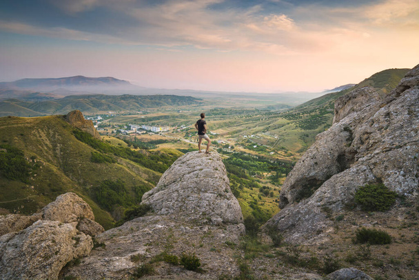 Young man standing on a rocky top and enjoy Crimea mountain valley. - Fotó, kép