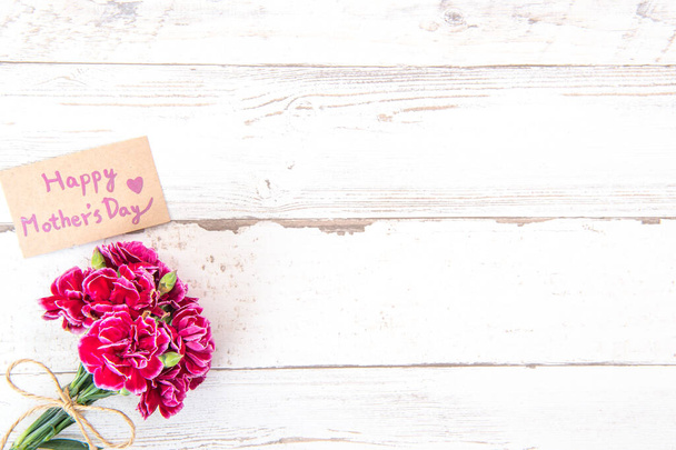 May mothers day concept photography - Beautiful carnations with template card isolated on a bright wooden table, copy space, flat lay, top view, mock up - Φωτογραφία, εικόνα