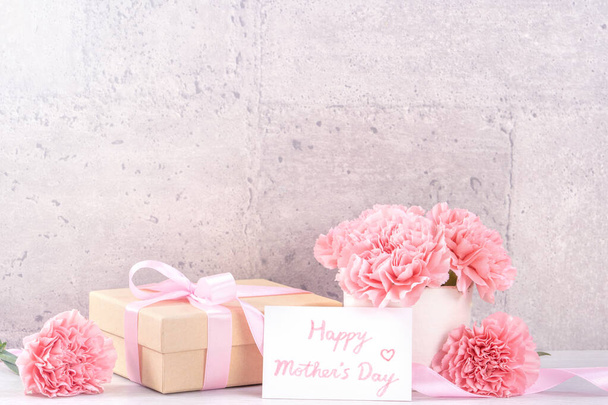 May mothers day handmade giftbox wishes photography - Beautiful blooming carnations with pink ribbon box isolated on fair-faced gray background desk, close up, copy space, mock up - Foto, afbeelding