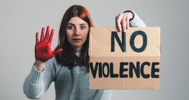 A lány felemeli a táblát, hogy nincs erőszak, és a kéz megállítja a háborút tiltakozásul. - Fotó, kép