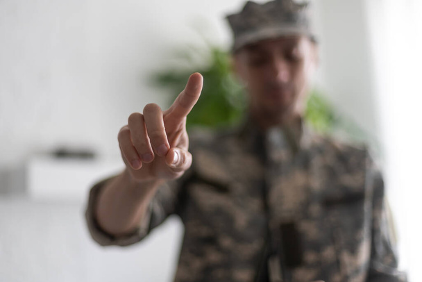 Soldado aislado sobre fondo blanco apuntando hacia atrás con el dedo índice. - Foto, imagen