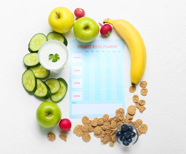 Еженедельный планировщик еды и различные здоровые продукты на легком фоне - Фото, изображение