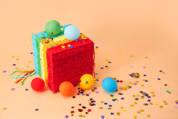 Piñata mexicana en forma de cubo, globos y confeti sobre fondo de color - Foto, Imagen